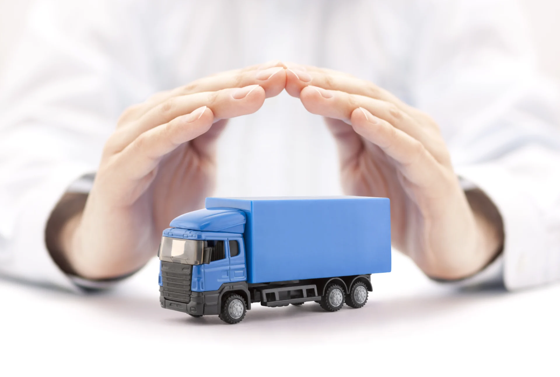 Hands protecting a blue toy truck.