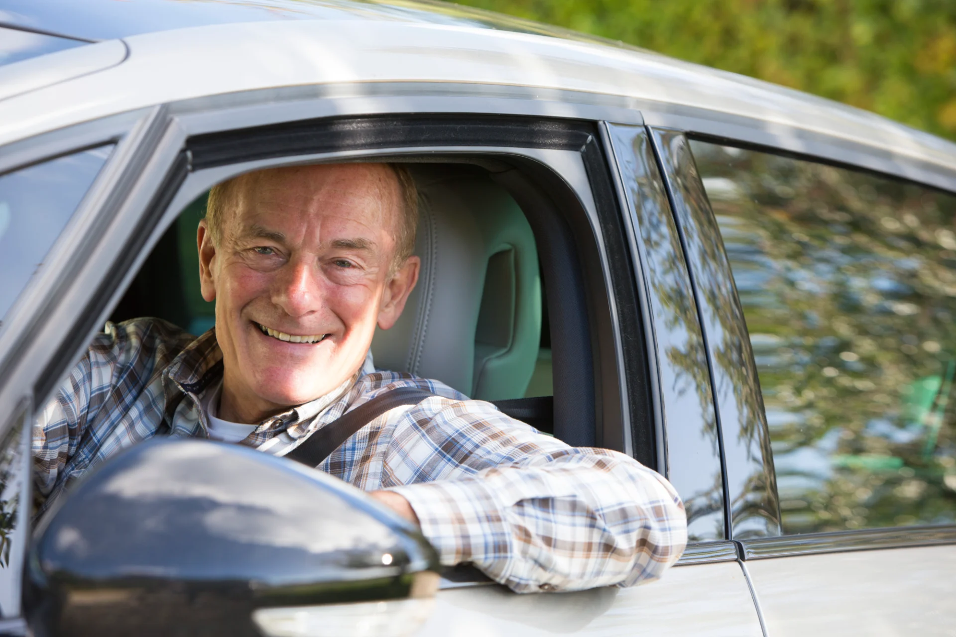 Smiling senior man driving a car.