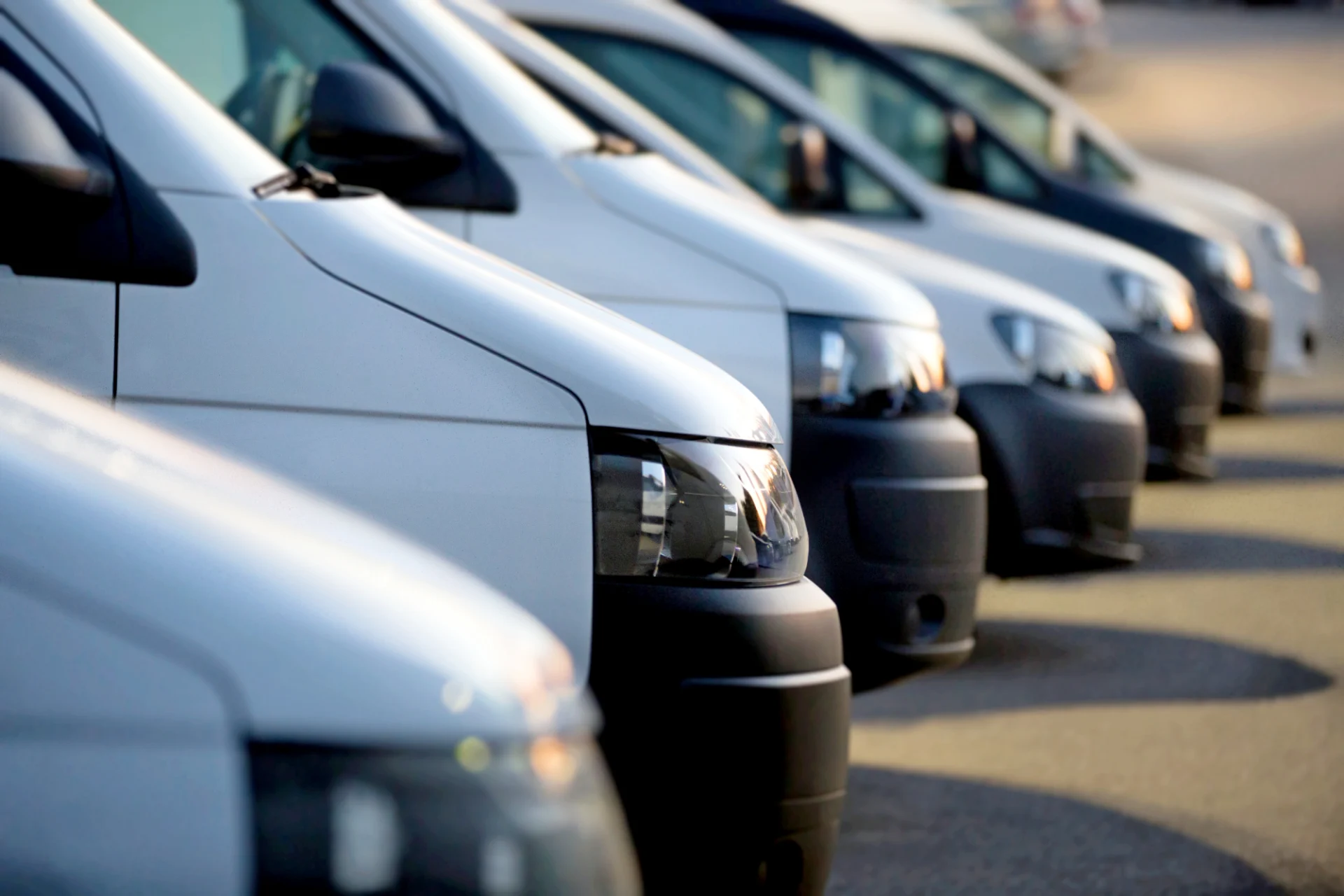 Row of white vans parked in a lot.