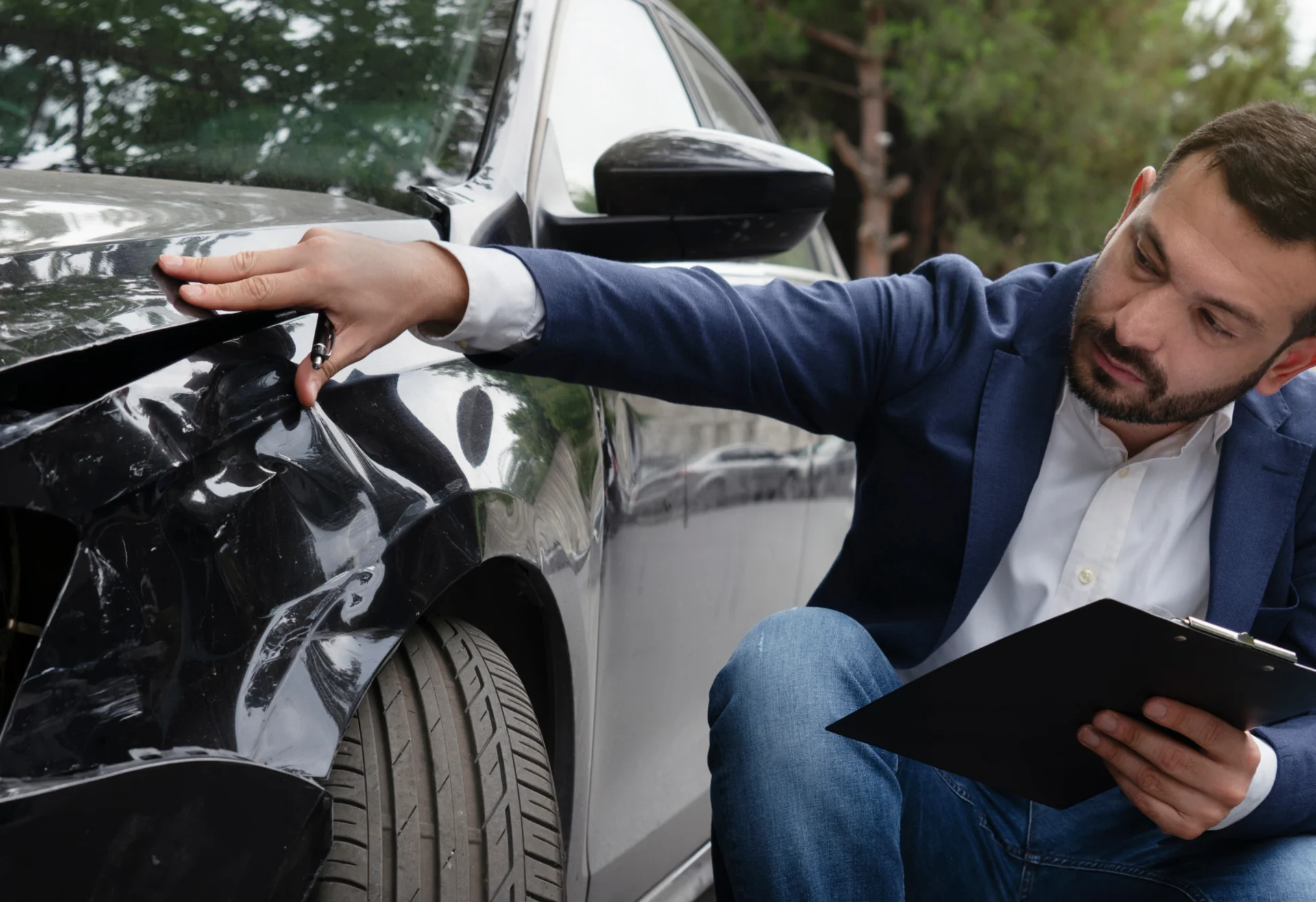 Man inspecting damage to a car.