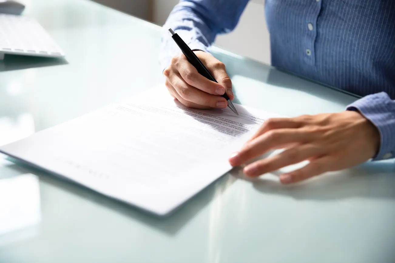 A person writing on paper with a pen.